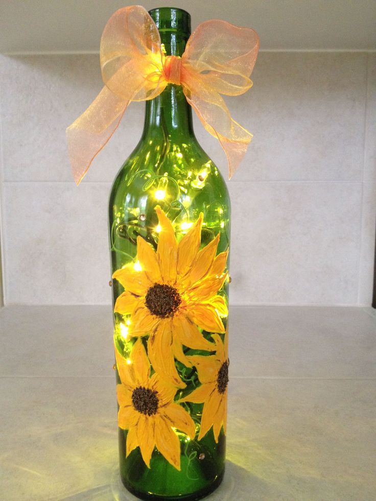 a green glass bottle with yellow sunflowers on it and a light up bow