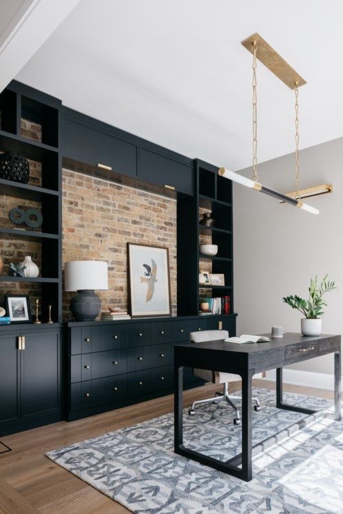 a living room with black bookcases and a white rug on the wooden floor