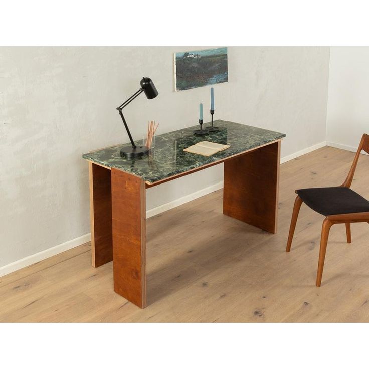 a desk with a chair next to it and a painting on the wall