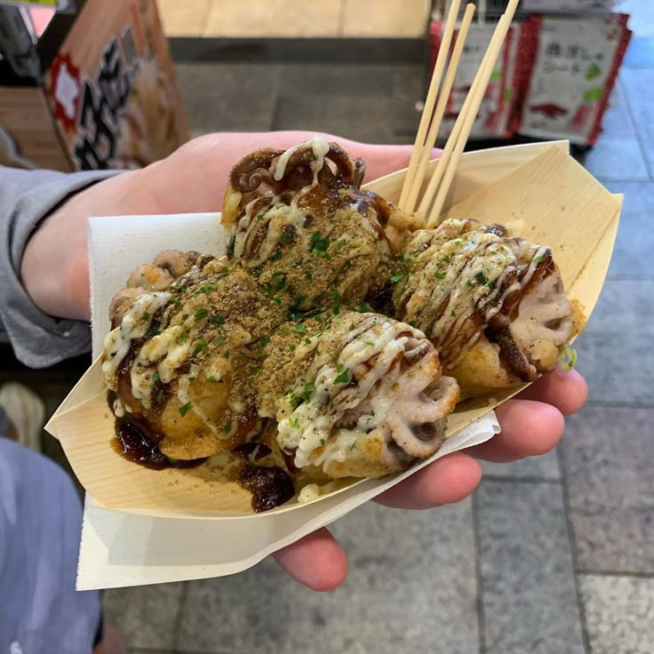 a person holding up some food with chopsticks