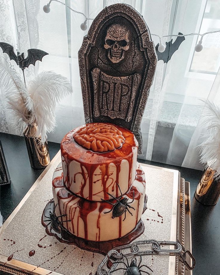 a halloween themed cake sitting on top of a table next to a tombstone and spider web decoration