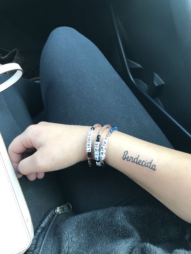 a person with three bracelets on their wrist in the back seat of a car