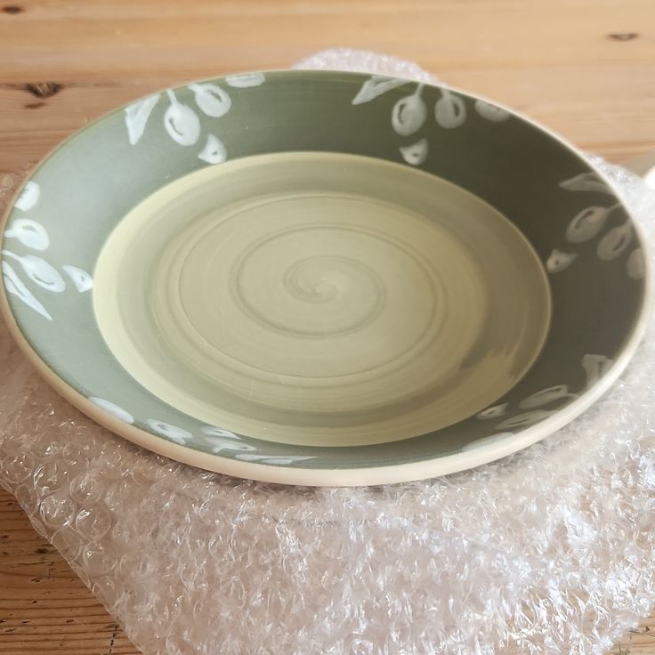 a green and white bowl sitting on top of a wooden table