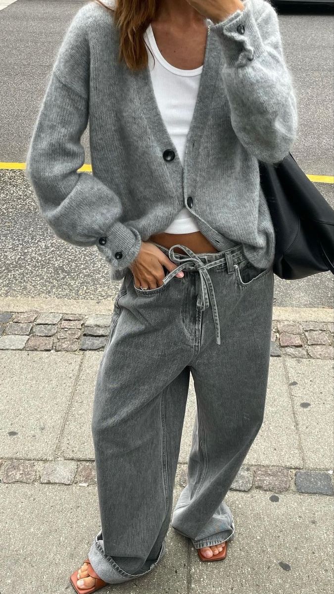 a woman is talking on her cell phone while wearing grey pants and a white shirt