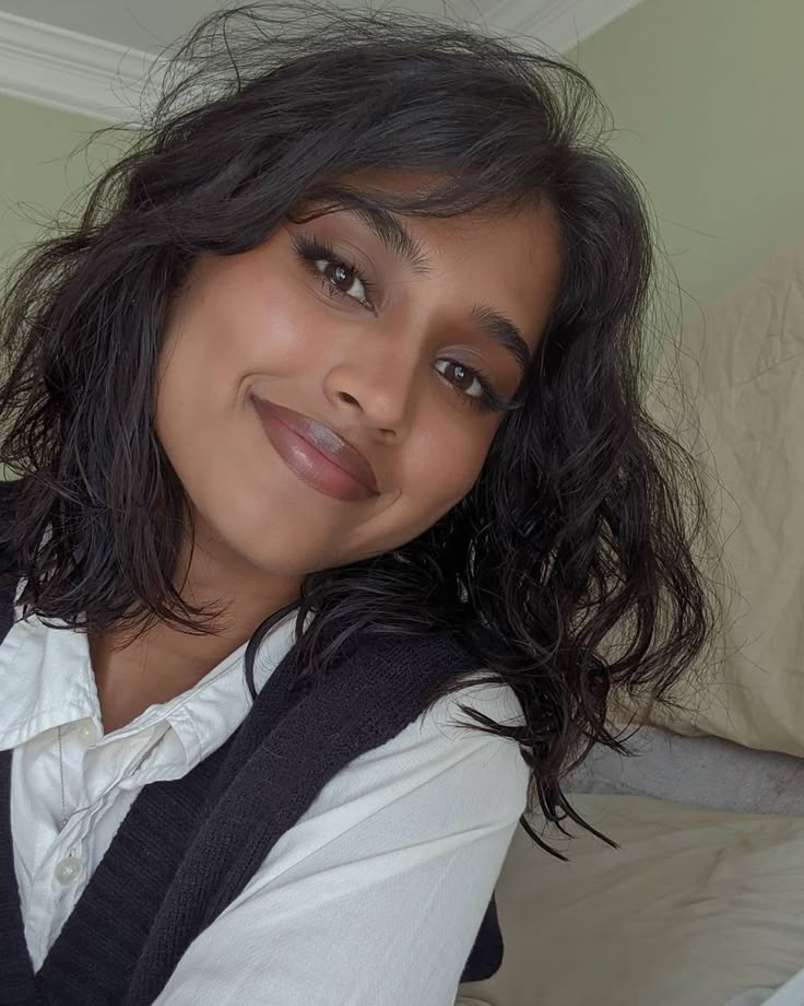 a woman is posing for a photo in her bedroom, wearing a white shirt and black vest