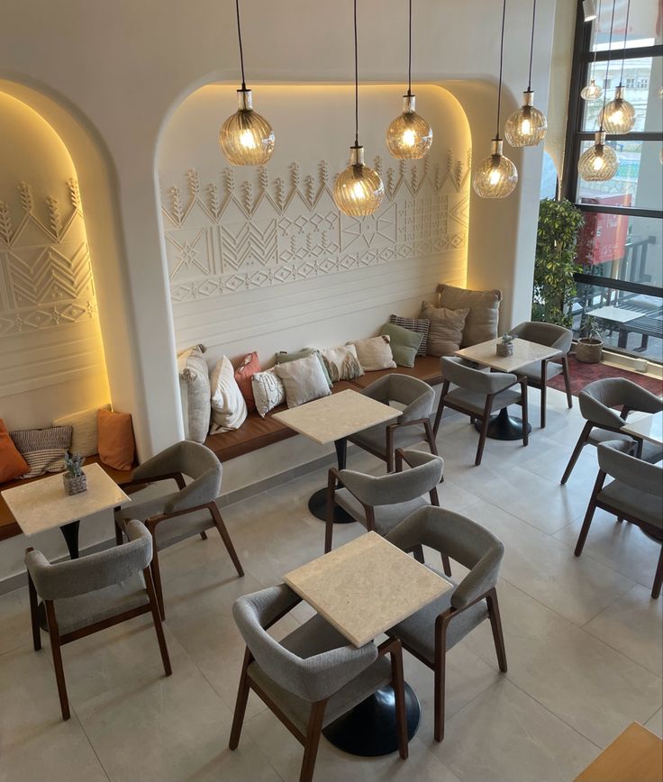 a restaurant with tables, chairs and lamps hanging from the ceiling above them is decorated with white tiles