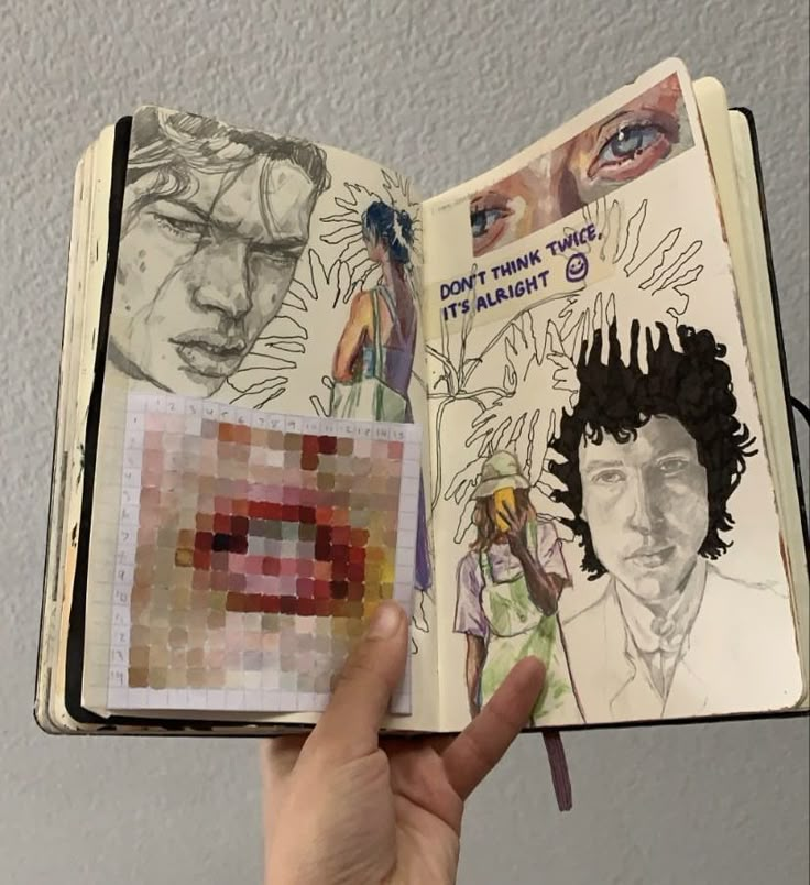 a hand holding an open book with drawings on it