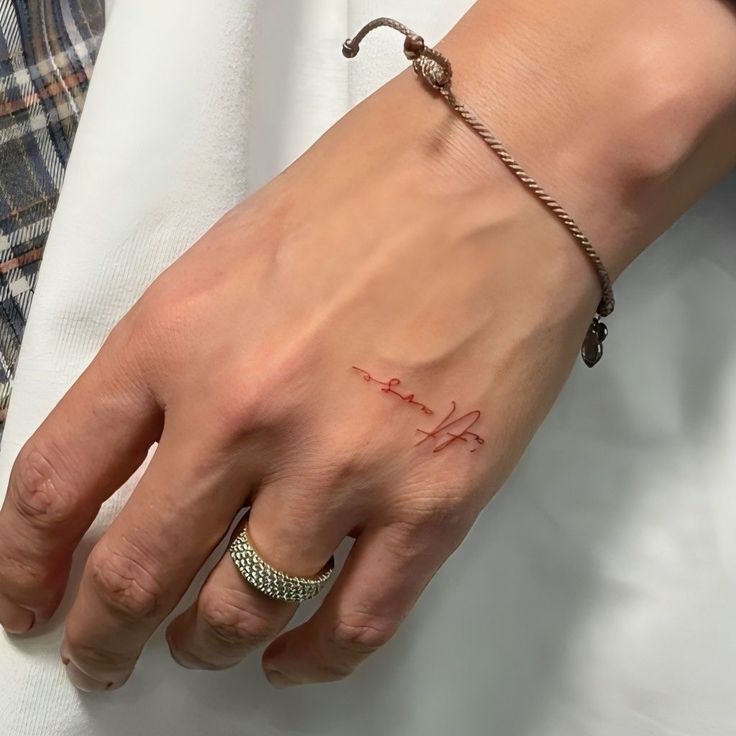 a woman's hand with a small tattoo on her left wrist and the word love written in red ink