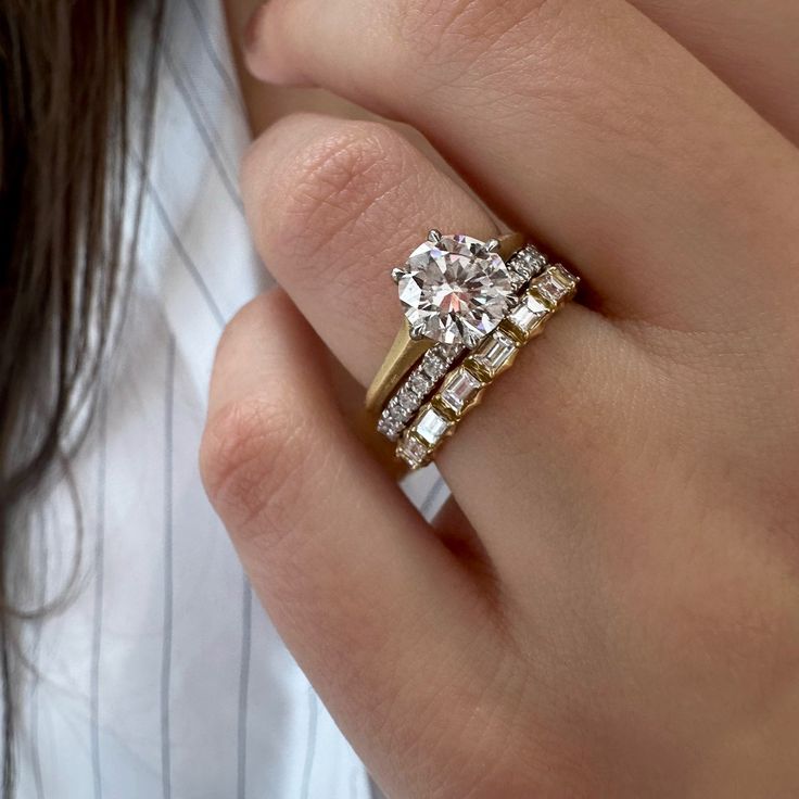 a woman's hand with a diamond ring on top of her finger and an engagement band