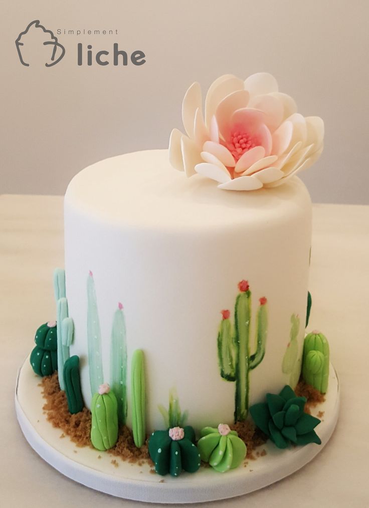 a white cake decorated with cactus and flowers