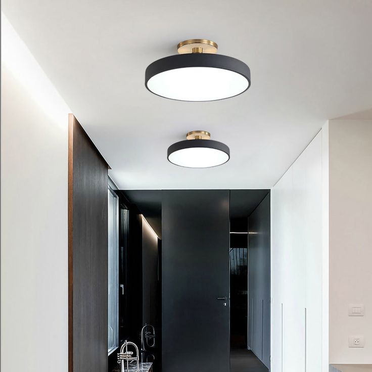 a hallway with black and white walls, two lights on the ceiling and an open door leading to another room