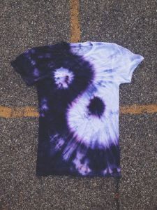 a purple and white tie - dye shirt laying on the ground next to a yellow line