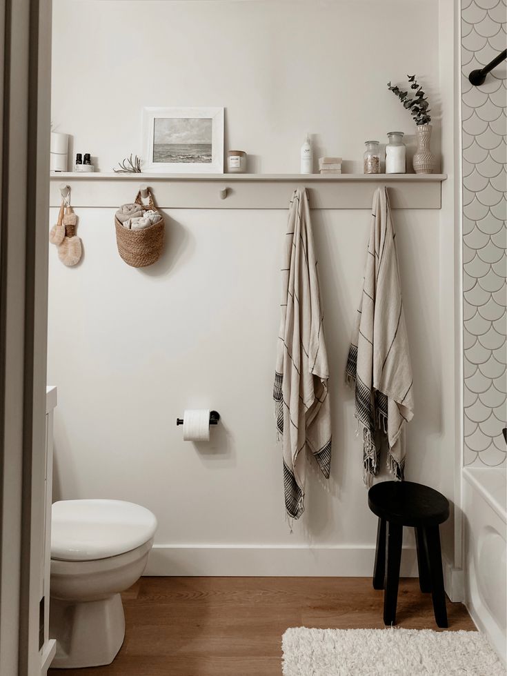 a white bathroom with two towels hanging on the wall and a toilet in the corner