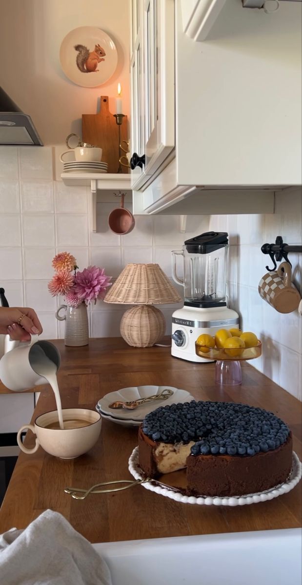 a person pouring milk over a cake on top of a wooden table in a kitchen