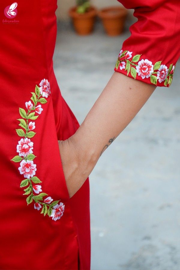 the woman is wearing a red dress with pink flowers on it and has her arm around another woman's waist