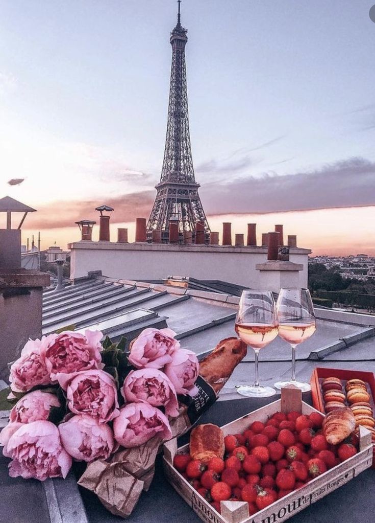 the eiffel tower is in the background with pink flowers and strawberries