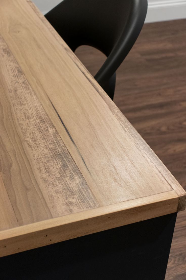 a wooden desk with a black chair in the background