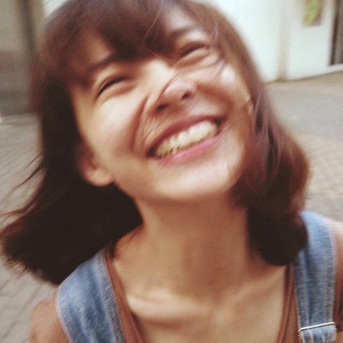 a woman smiling and holding a cell phone to her ear