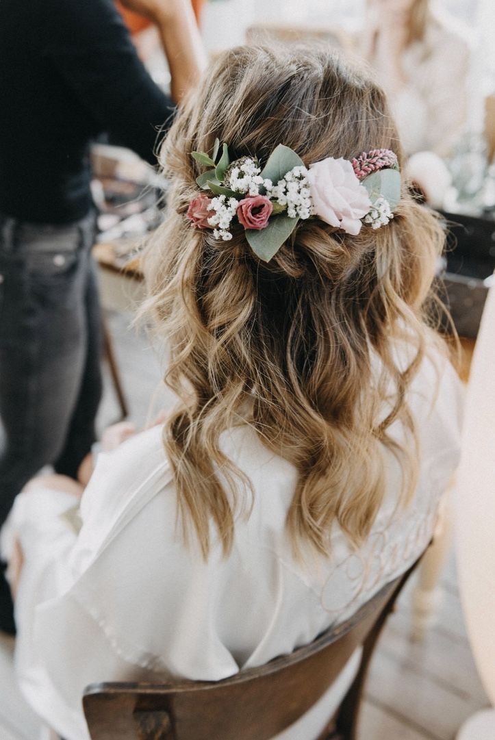 the back of a woman's head with flowers in her hair, sitting at a table