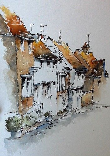 a drawing of some houses with watercolors on paper in the foreground and an orange sky behind them