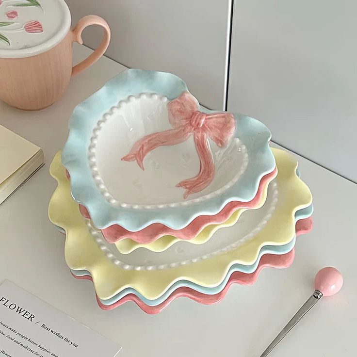 two plates with pink bows on them are sitting on a table next to a cup and saucer