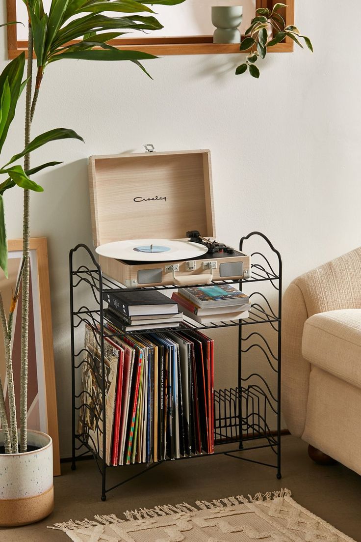 a record player sitting on top of a metal stand next to a potted plant