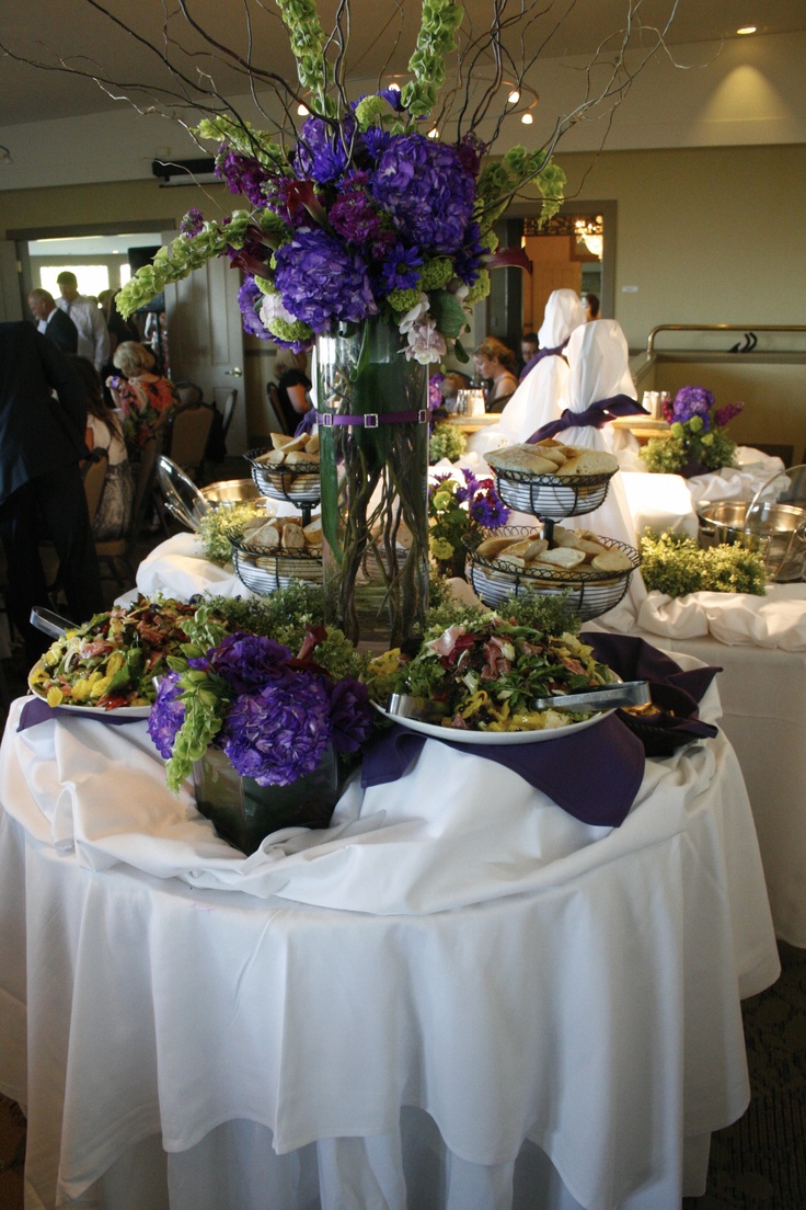 a table topped with lots of plates filled with different types of food and flowers in vases