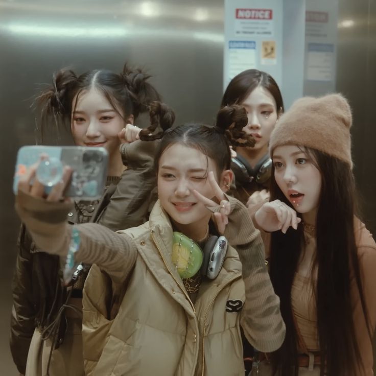 group of young women taking selfies in an airport elevator with their cell phones up to their ears