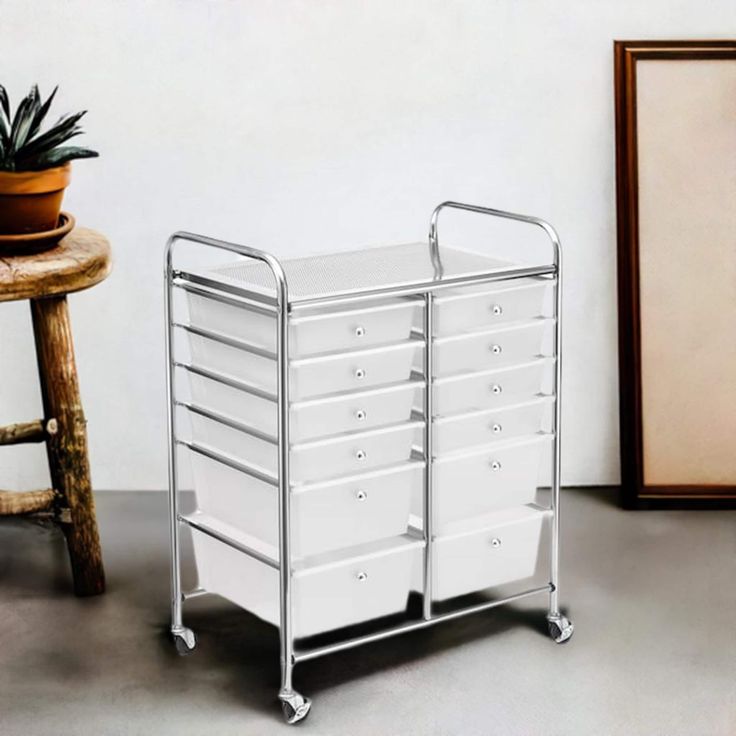 a white storage cart sitting next to a potted plant on top of a table