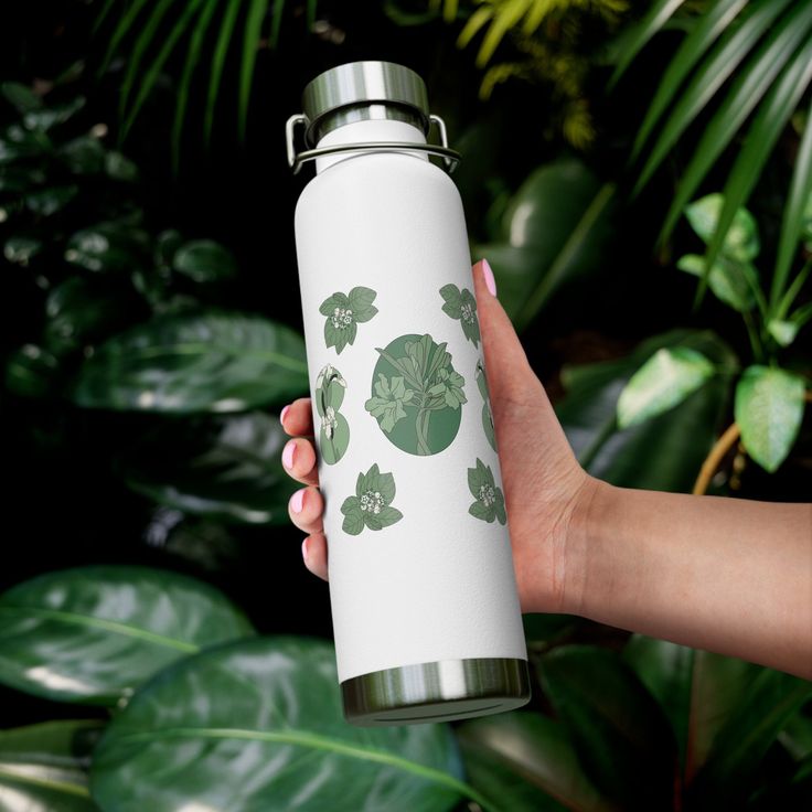 a person holding a white and green flask with shamrocks on it in front of some plants