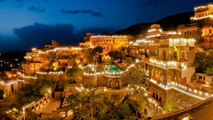 an aerial view of a city at night with lights on the buildings and trees in the foreground