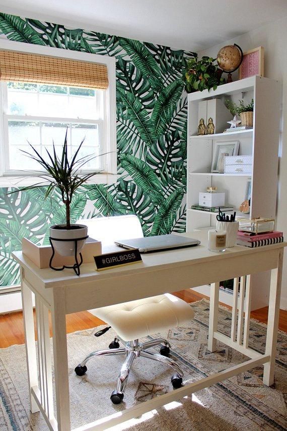 a white desk topped with a laptop computer sitting next to a green leafy wallpaper