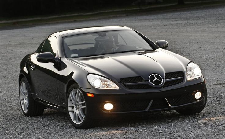 a black mercedes slk is parked in the parking lot with its hood up and lights on