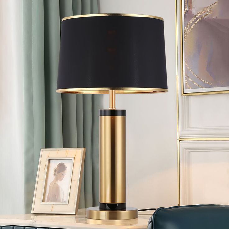 a lamp that is sitting on top of a table next to a framed photo and a purse