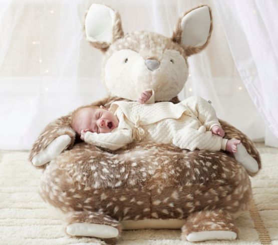 a baby is laying on top of a stuffed animal that looks like a deer's head