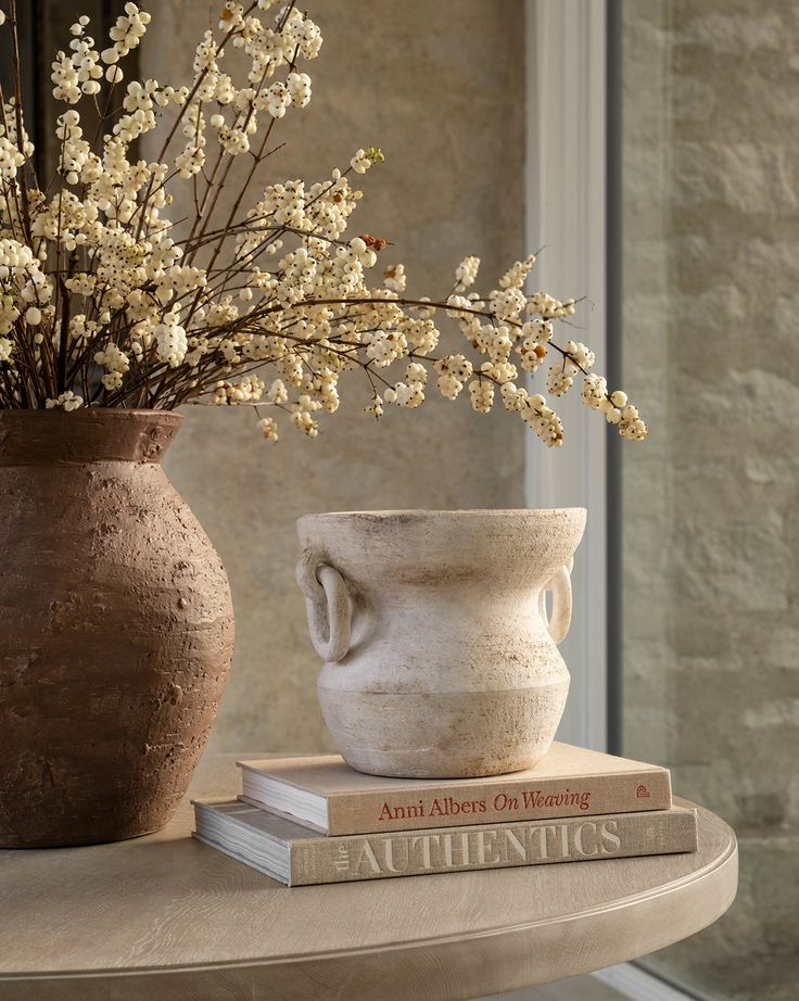 two vases sitting on top of a table next to each other with flowers in them