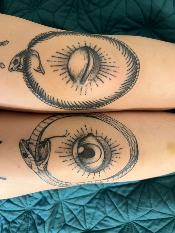 two people with tattoos on their legs, one has an eye and the other has a sun