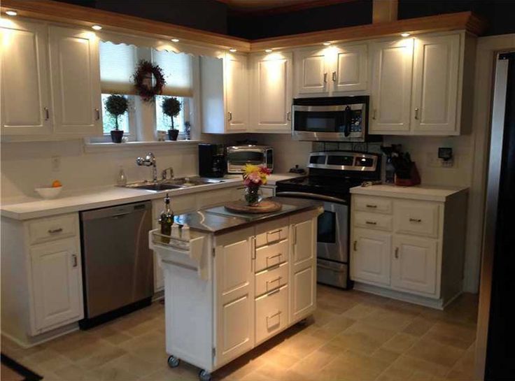 a kitchen with white cabinets and stainless steel appliances in the center, along with an island