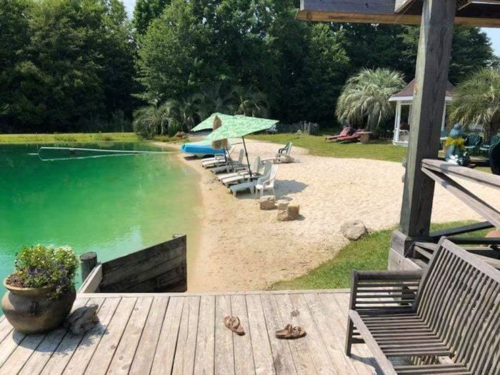 a wooden deck with chairs and umbrellas next to a lake filled with green water