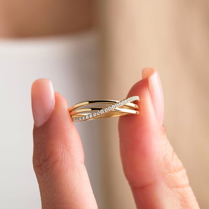 a woman holding a gold ring with diamonds on it's sides and the end of her finger