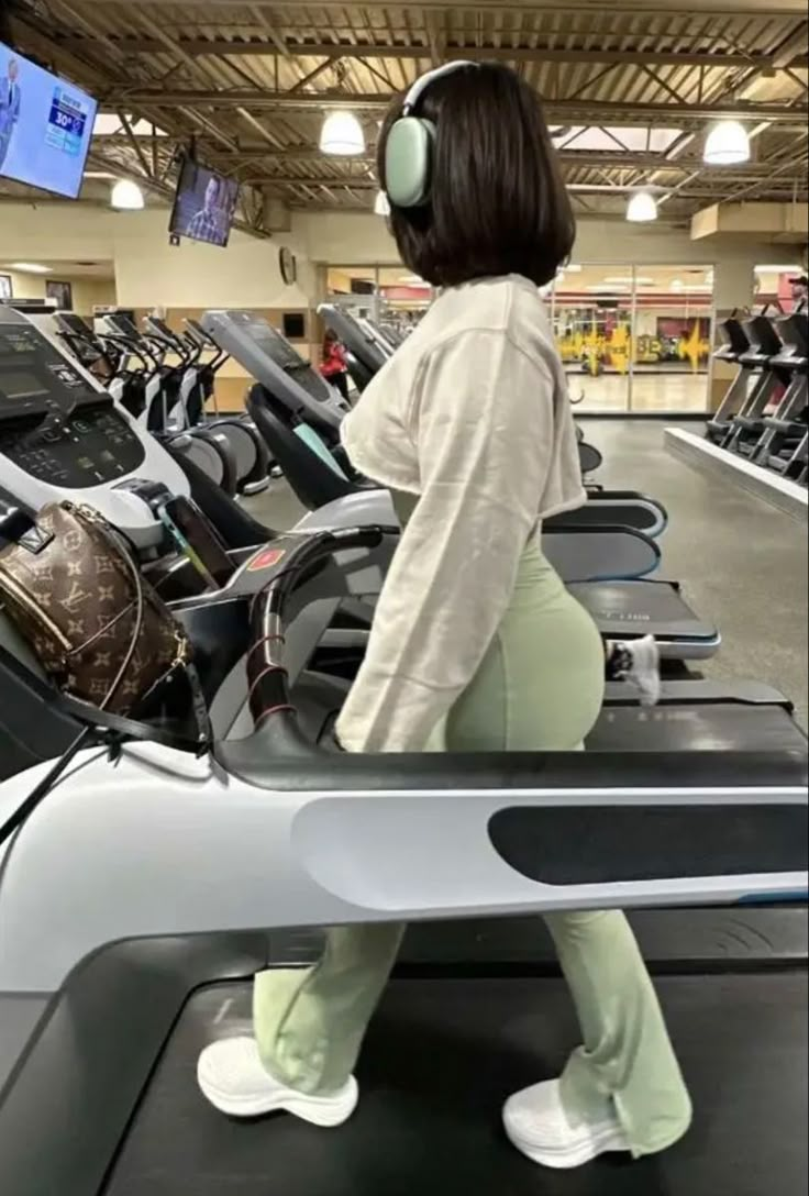 a woman with headphones is on a treadmill and listening to music in the gym