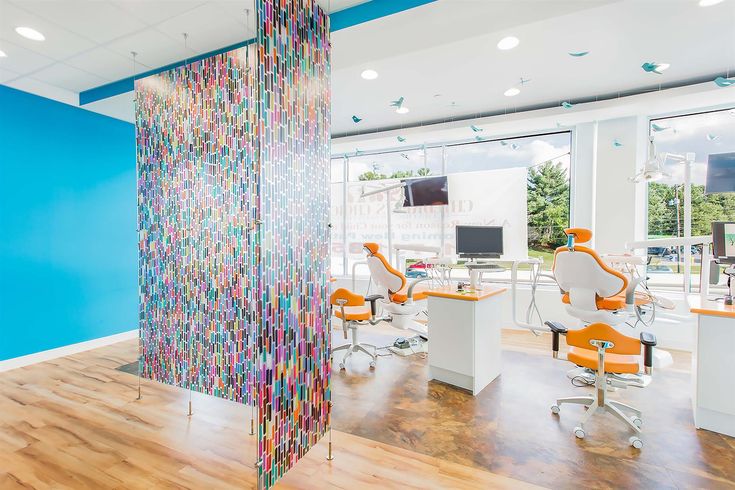 an office with chairs, desks and a colorful wallpapered divider in the center