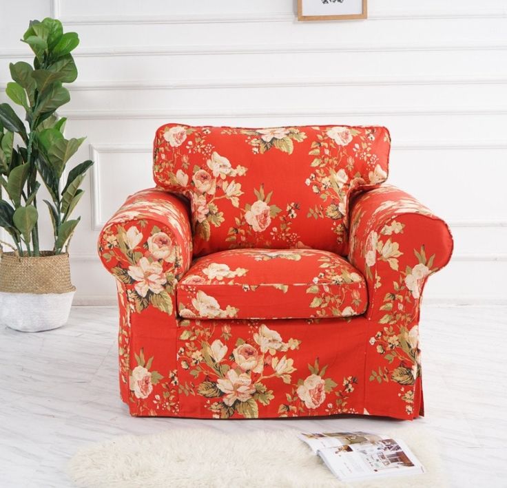 a living room with a red floral chair and potted plant on the floor next to it