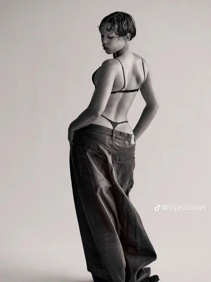 black and white photograph of a woman with her back to the camera, standing on a skateboard