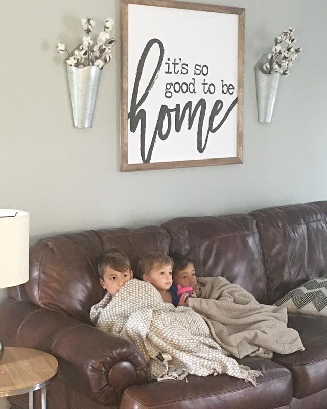 two children are sitting on a couch in front of a sign that says it's so good to be home