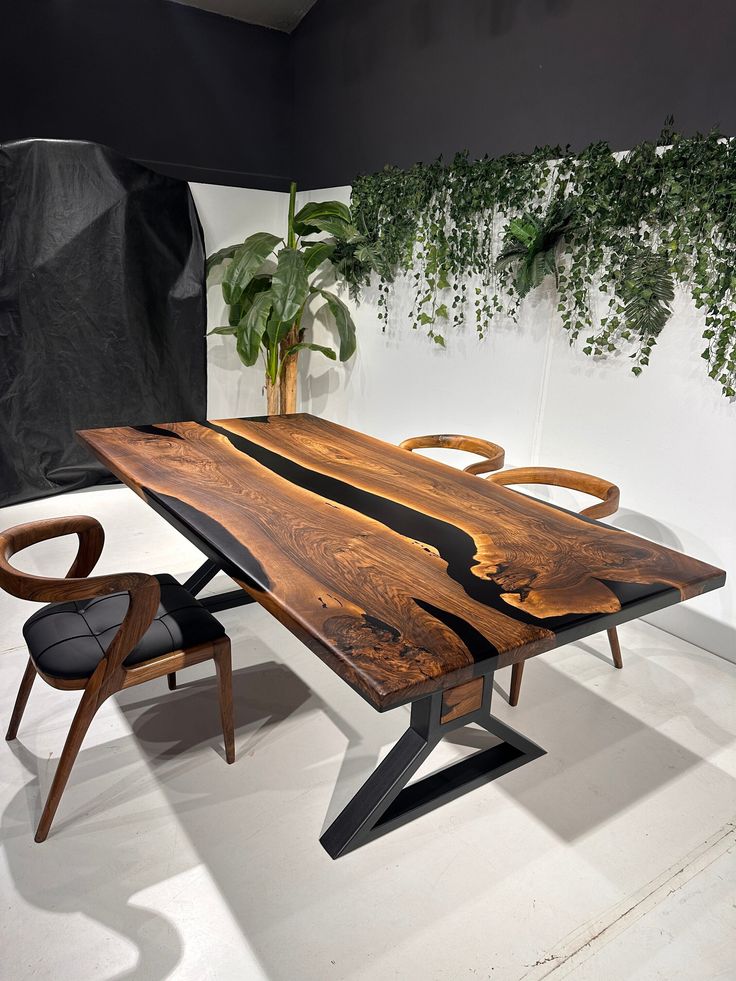 a wooden table sitting next to a chair on top of a white floor covered in plants