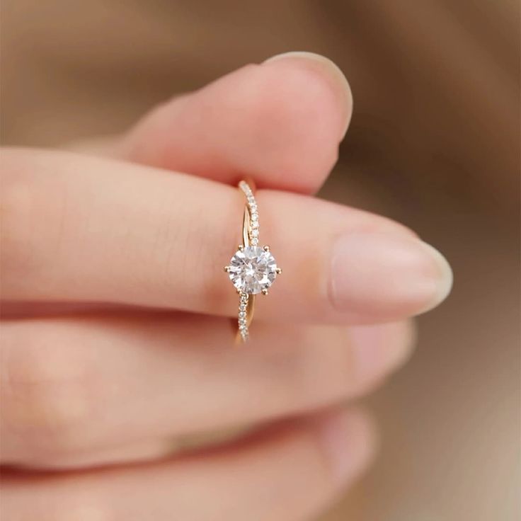 a woman's hand holding an engagement ring with a diamond in the shape of a flower