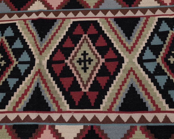 an old rug with many different colors and patterns on it's sides, including black, red, green, blue, beige