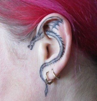 a woman's ear with a dragon tattoo on it