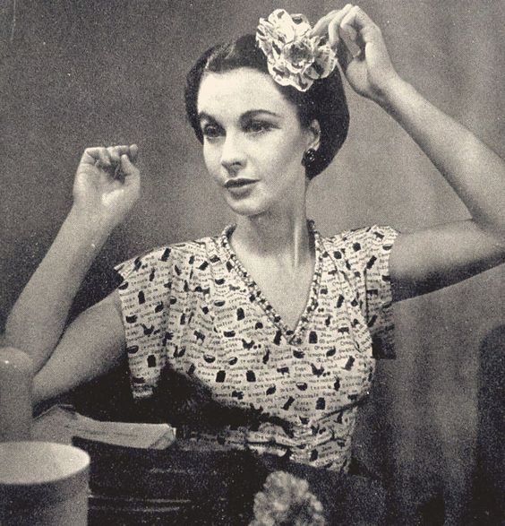 an old black and white photo of a woman with a flower in her hair